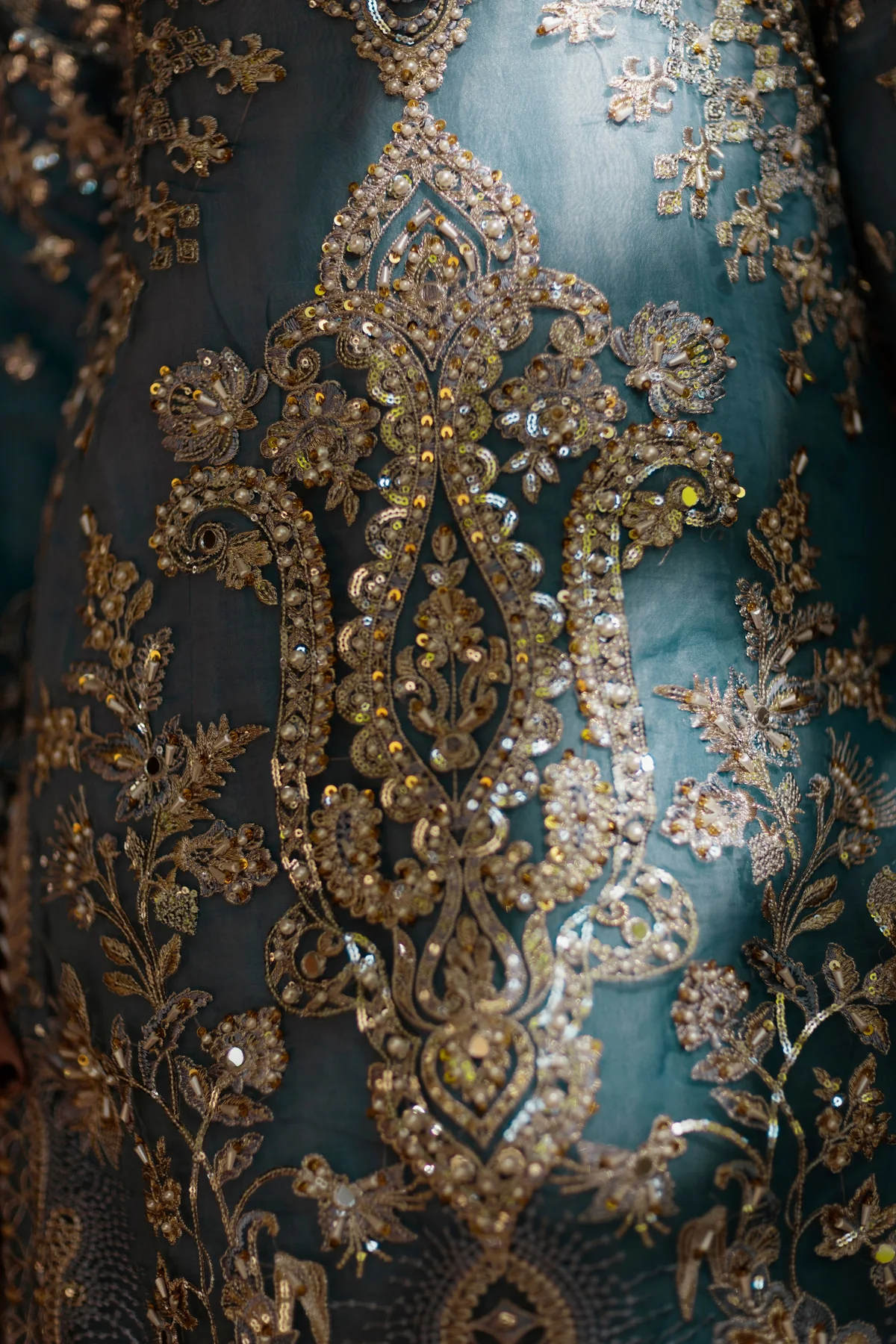 Gold-toned floral and scrolling details on teal fabric.