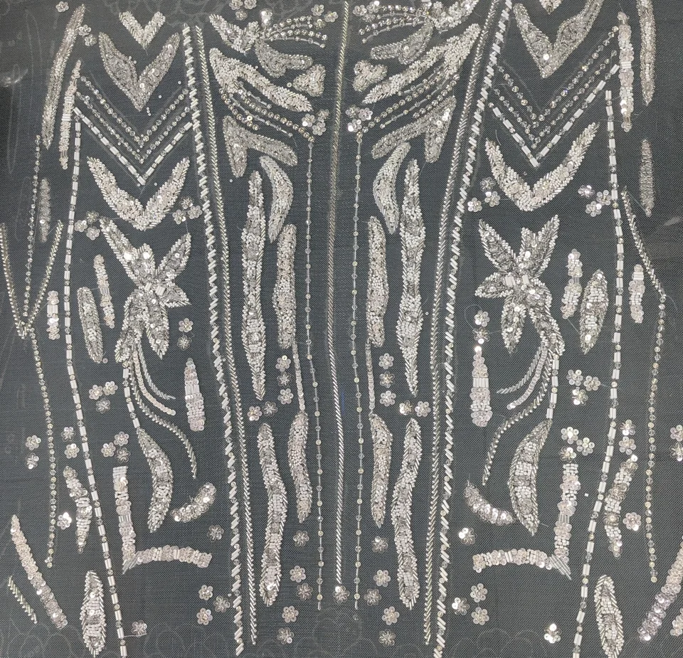 Pale reflective geometric lines, leaves and small flowers arranged symmetrically on dark net.