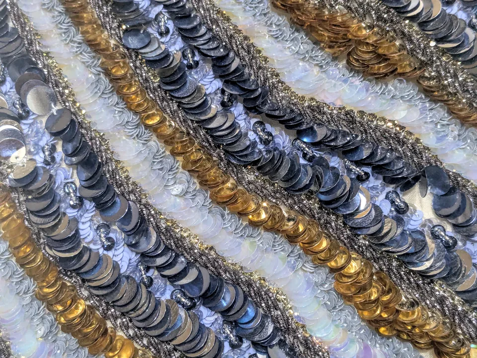 Close-up of overlapping reflective discs in dark, pale and gold-toned stripes.