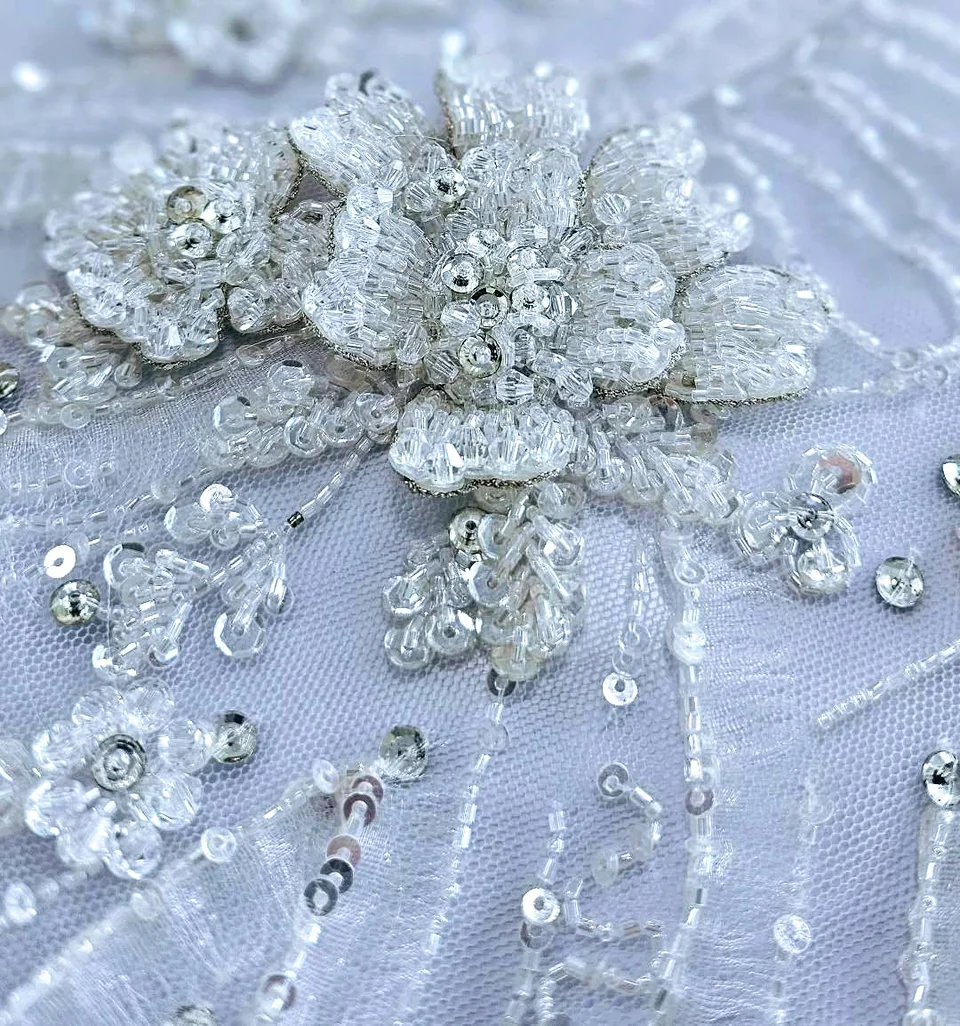 Close-up of raised, light-catching flowers and fine winding lines on a pale ground.
