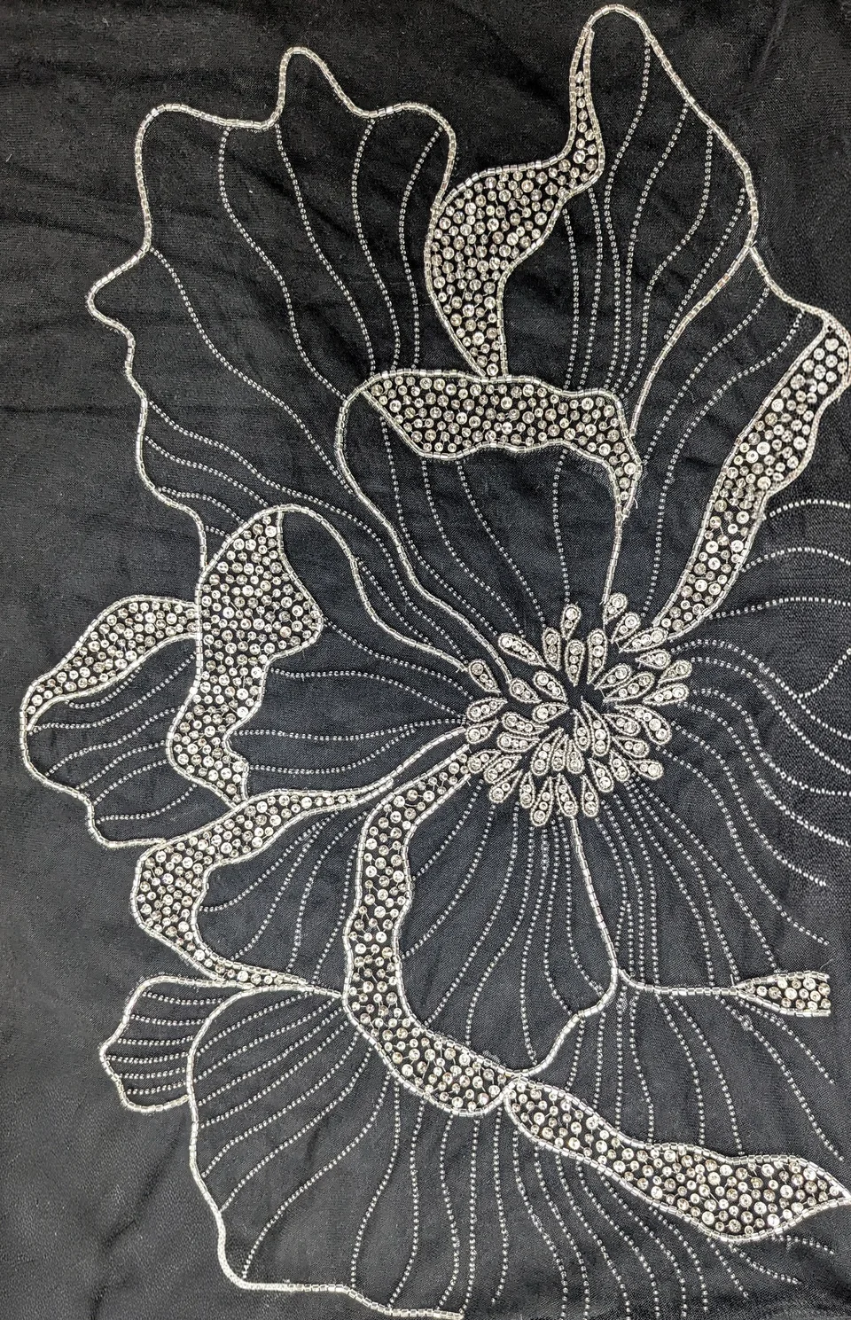 Large flower outlined in pale reflective lines and rounded accents against a dark ground.