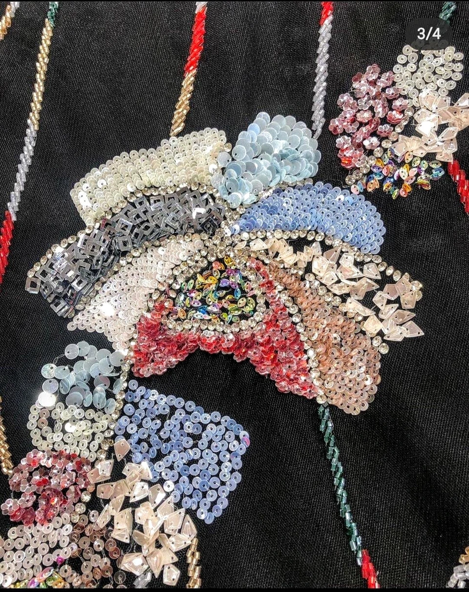 Multicoloured floral bead and sequin embroidery with pastel blue, pink and silver-toned petals on black fabric.