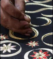 An artisan hand-embroidering floral motifs on dark fabric