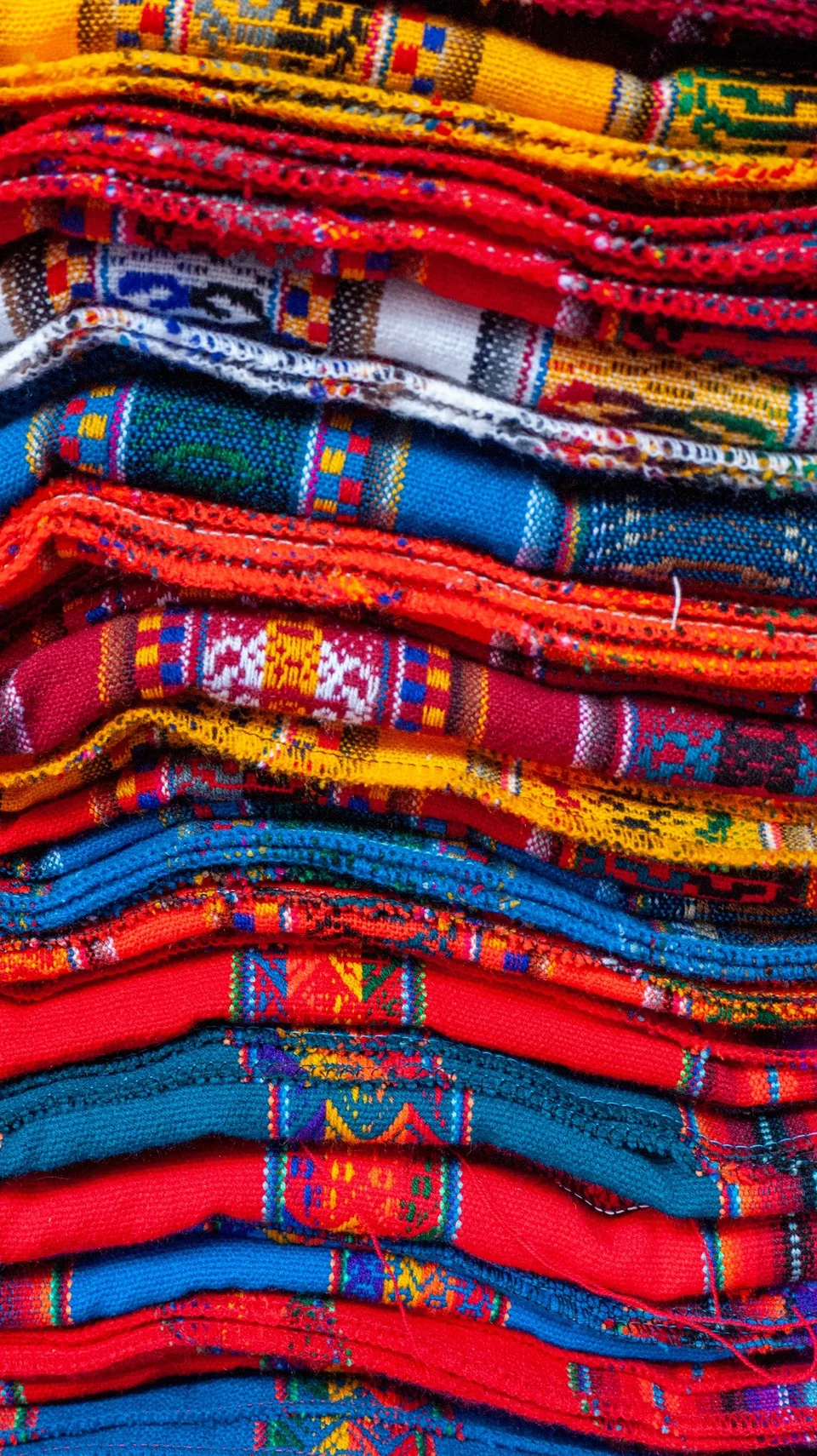 Layers of colourful woven textiles with visible threads and geometric patterns.